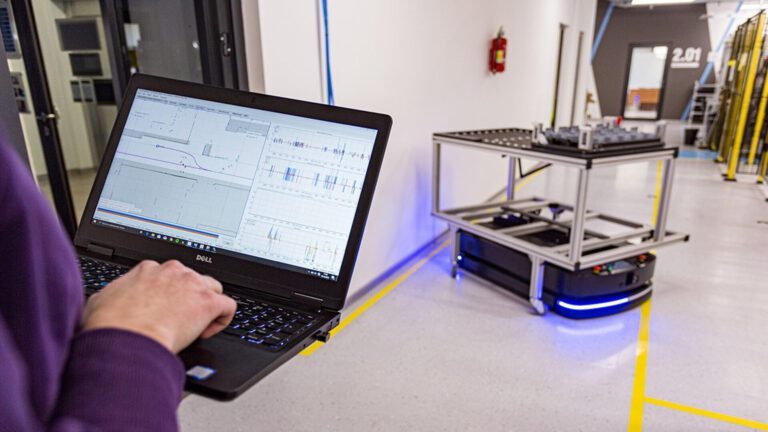 Obraz przedstawia robota AMR i system zarządzający Aformic w ekranie laptopa.